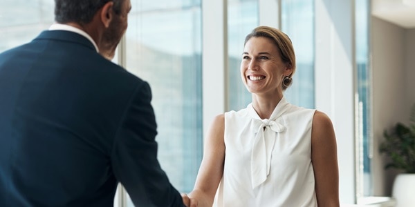 A smiling woman shaking someone's hand.